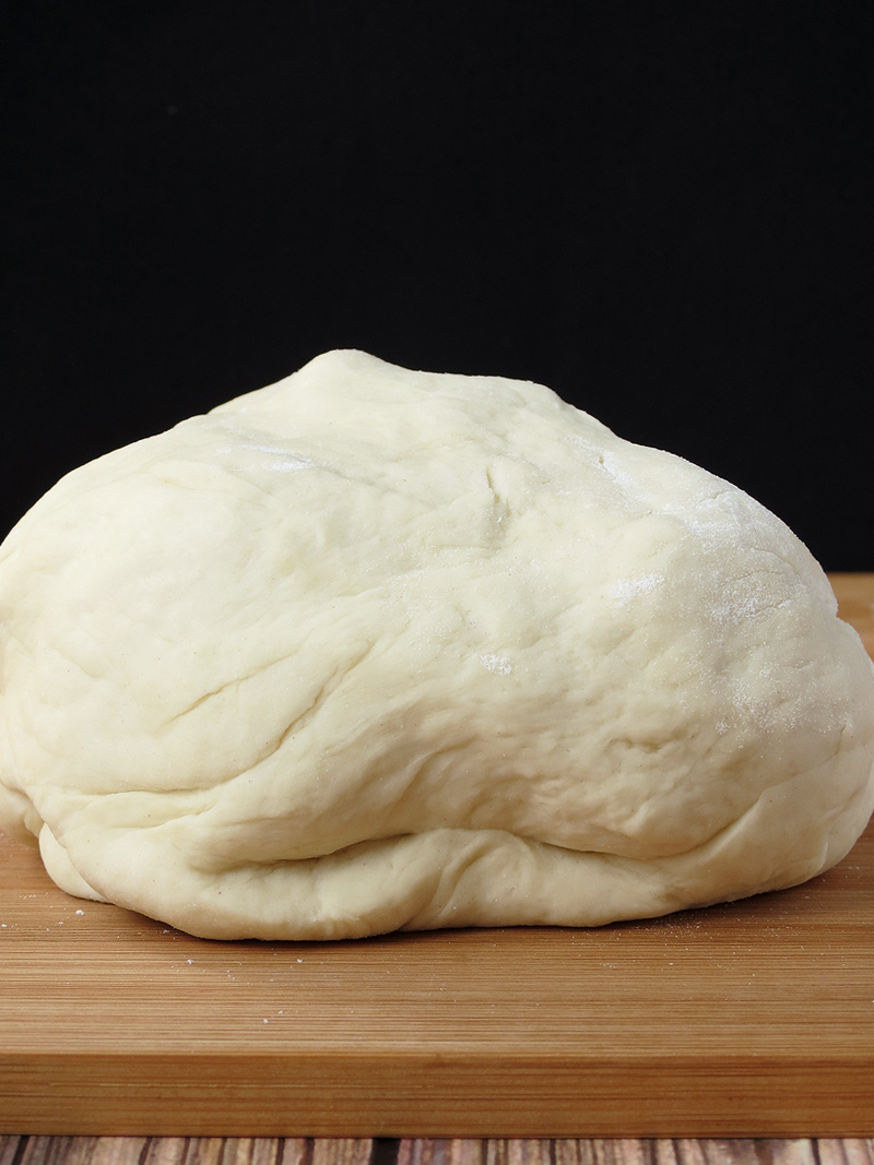Pizza dough kneaded on the wooden counter