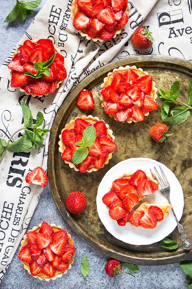 Celebrate summer with these full of flavor Strawberry Custard Tartlets! Lemon-y tart shells filled with creamy custard and topped with fresh strawberries and mint leaves! | yummyaddiction.com