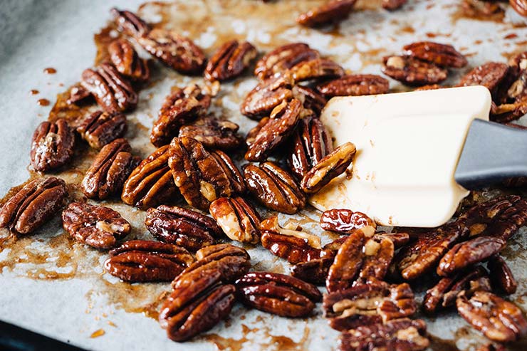 Rearranging honeyed pecans using a spatula before baking for 5 more minutes