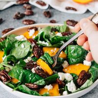 Lifting a forkful of the persimmon, feta, and honey roasted pecan salad