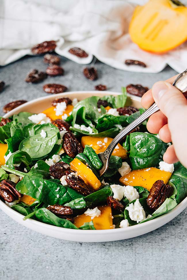 Lifting a forkful of the persimmon, feta, and honey glazed pecan salad