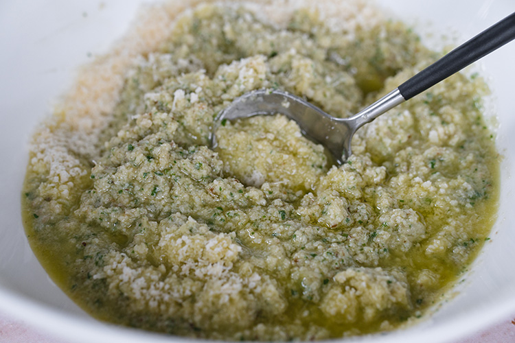 Adding Parmesan cheese to artichoke pesto and mixing everything together