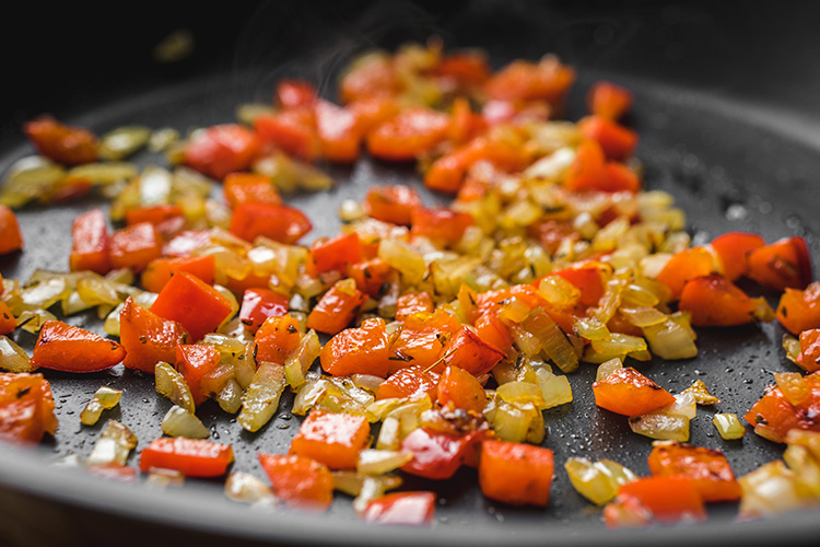Frying onion and red bell pepper in a pan