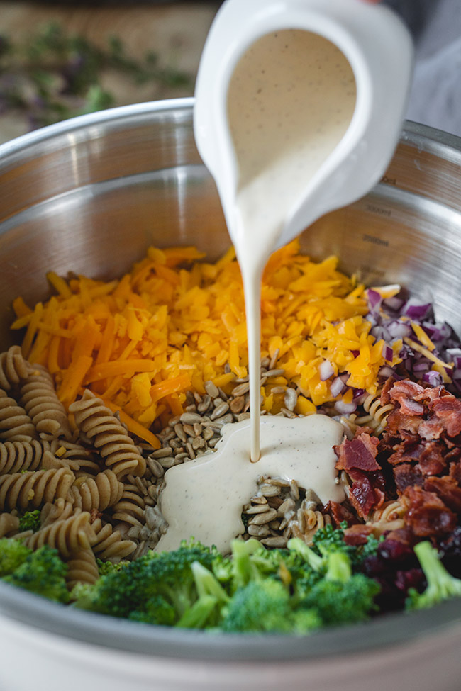 Pouring the creamy dressing into the cranberry pasta salad