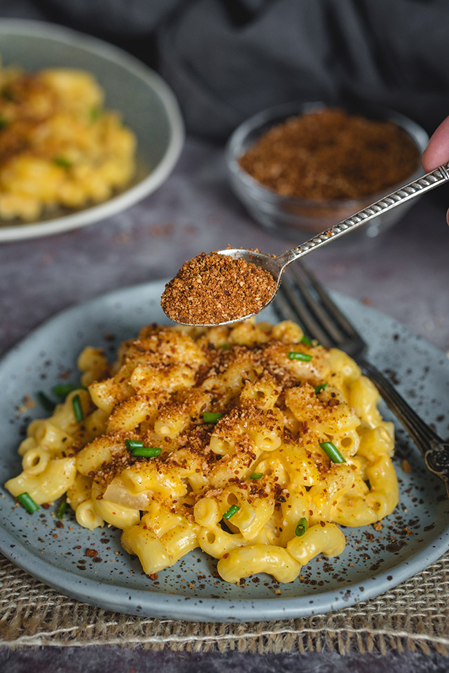 Spooning the kimchi topping over a plateful of mac and cheese