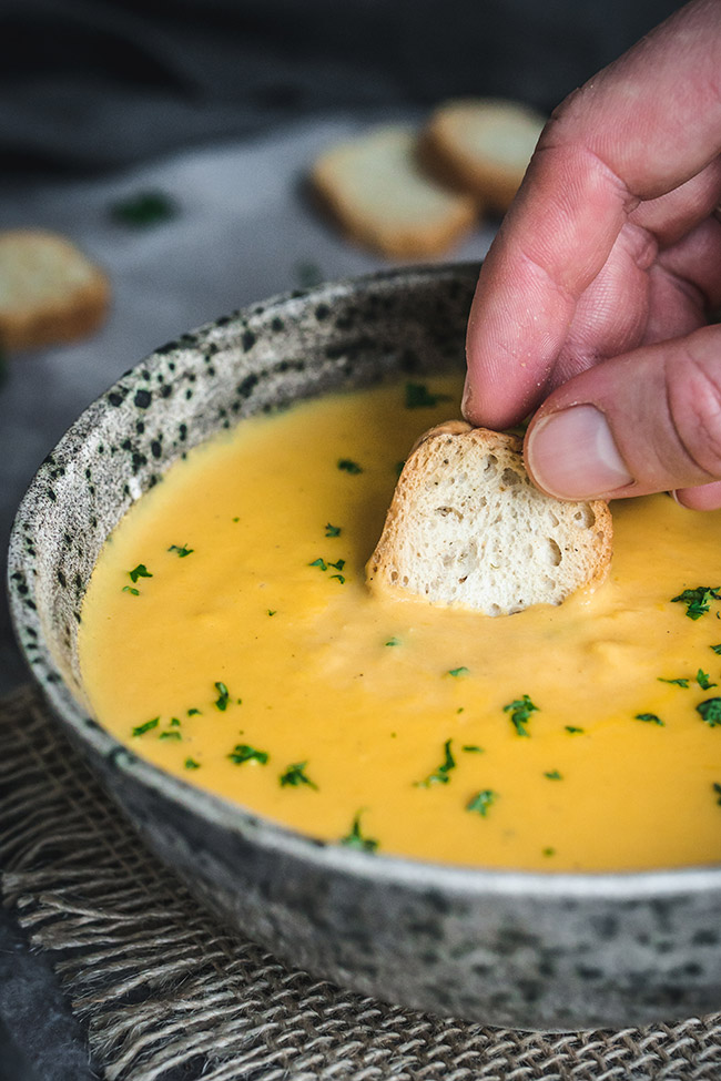 Dunking bread in a yellow carrot and turnip soup