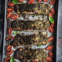Baked pesto salmon with tomatoes on a tray