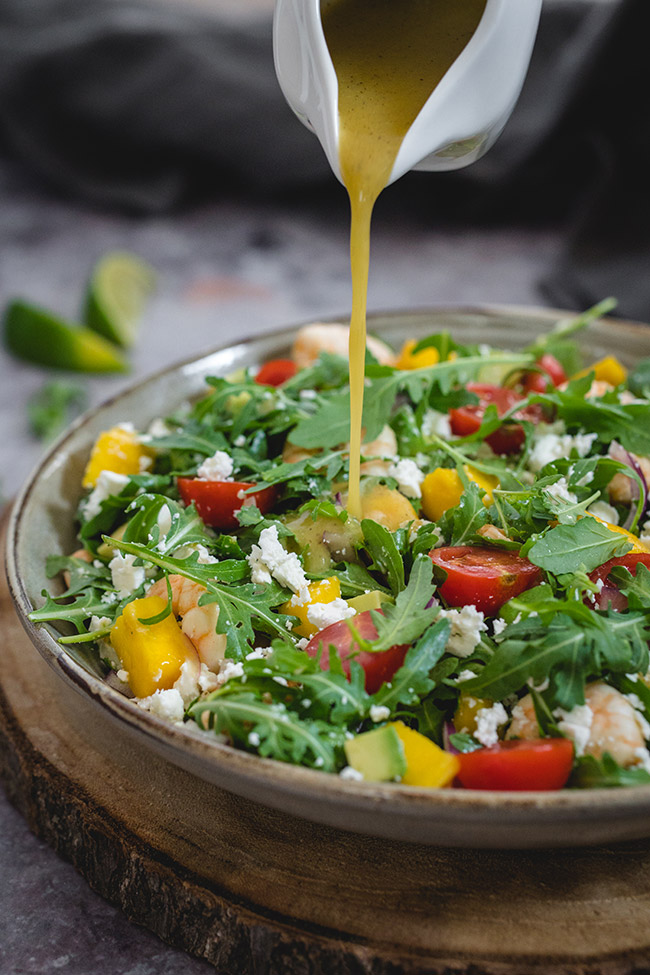 Pouring dressing onto shrimp mango salad