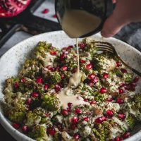 Pouring tahini dressing onto roasted romanesco