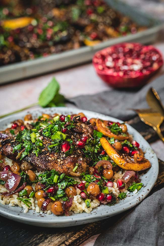 Pomegranate chicken served on bulgur with roasted chickpeas and herb salad