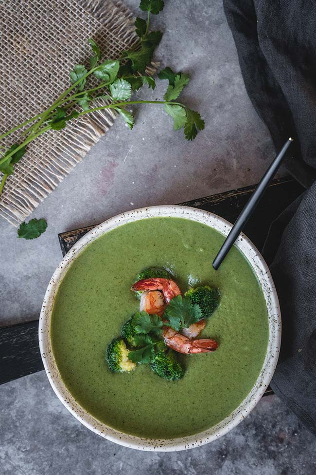 A bowl of broccoli coconut milk soup garnished with shrimp and cilantro