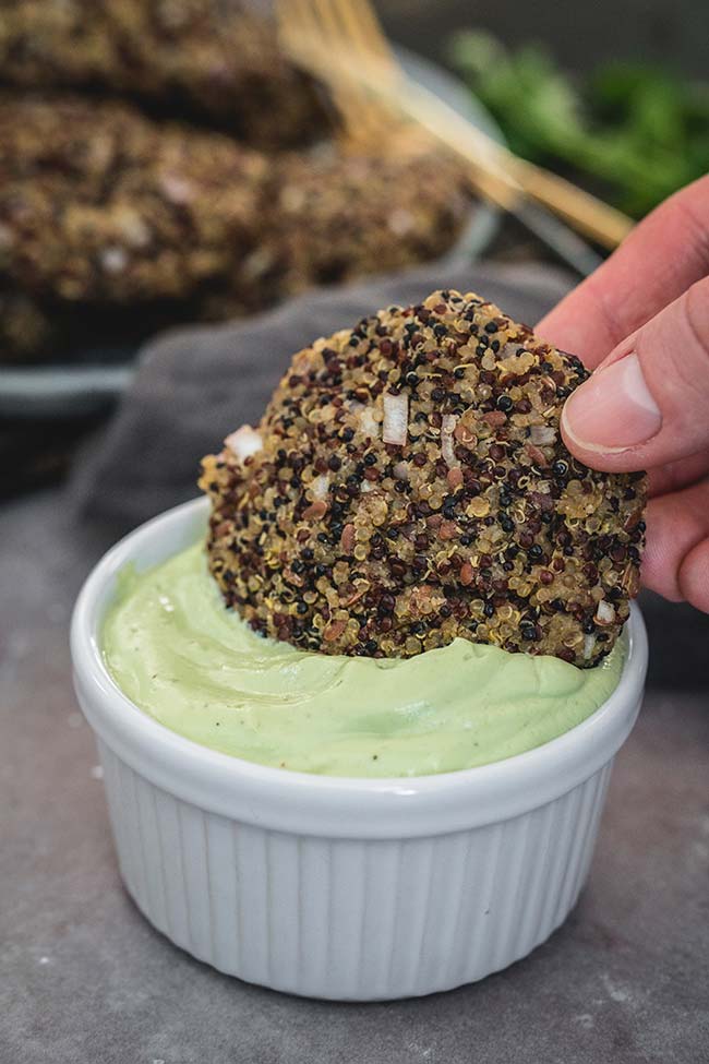 Dipping vegan quinoa patties in the avocado lime dip