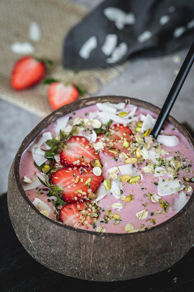 Healthy strawberry banana smoothie bowl topped with oats and coconut