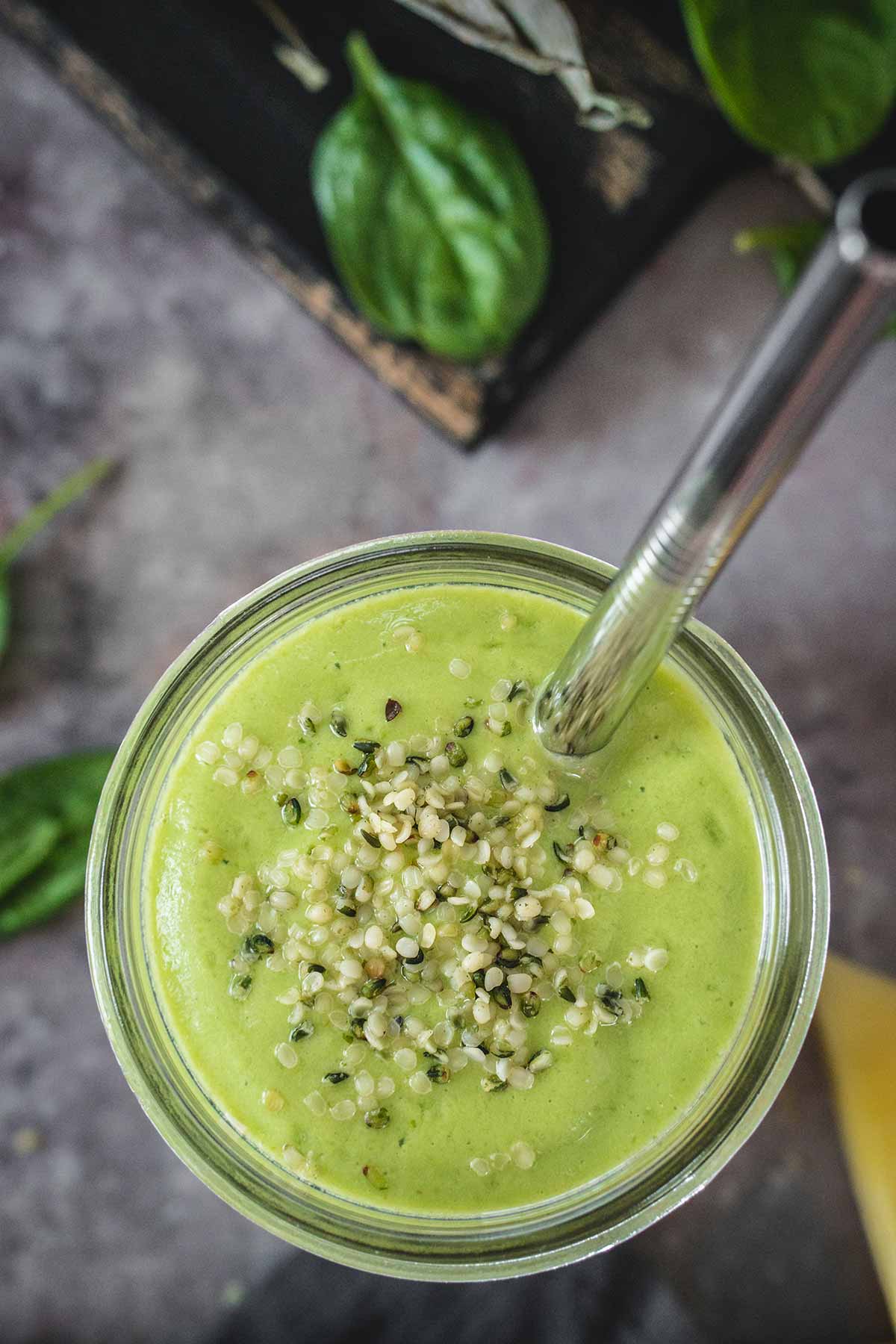 Avocado spinach pineapple smoothie sprinkled with hemp seeds overhead shot