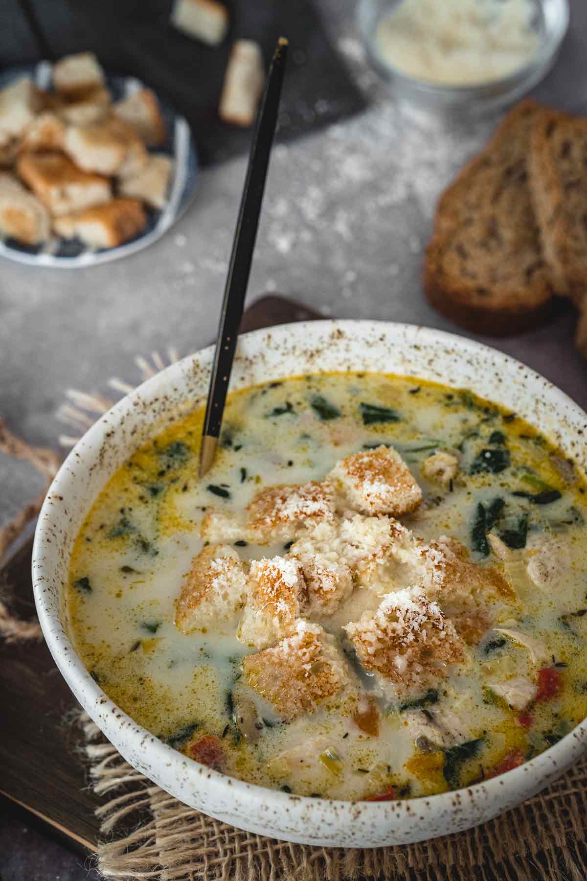 Creamy chicken florentine soup in a bowl served with croutons and parmesan