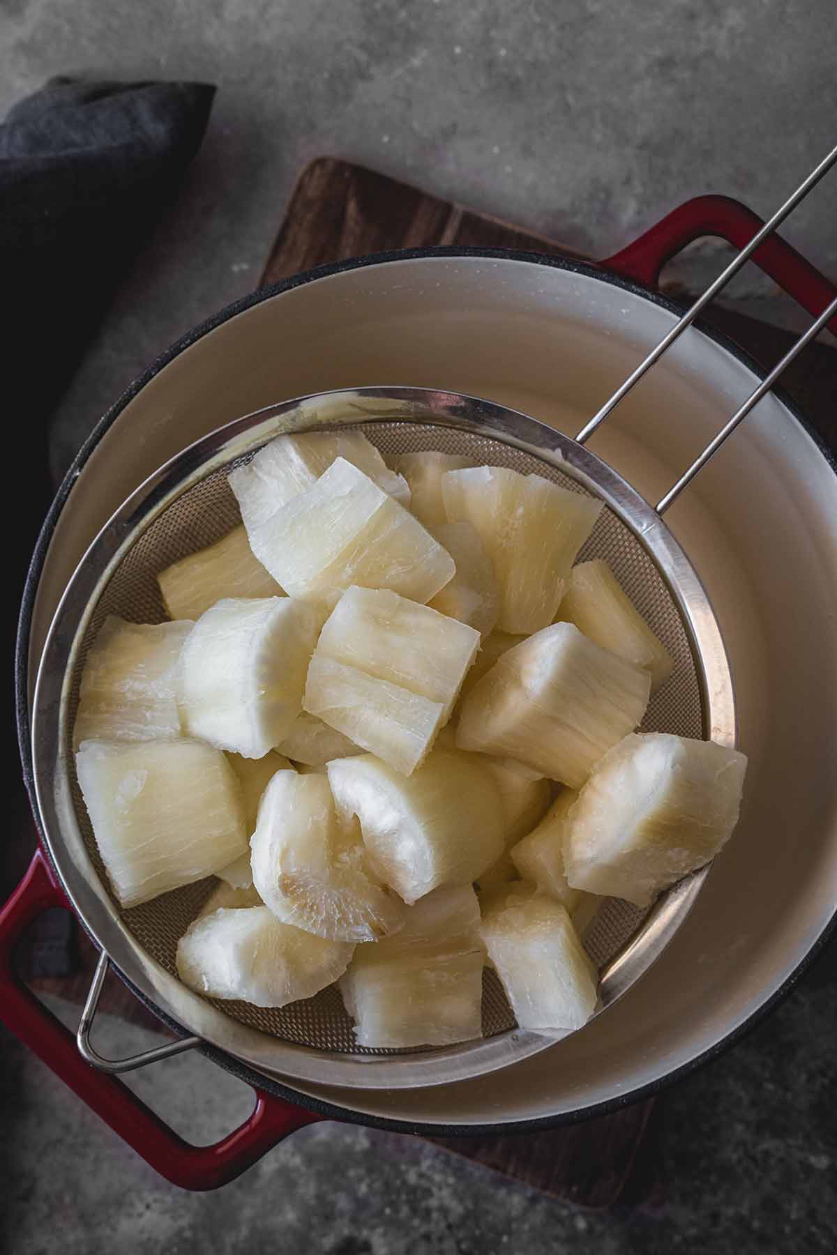 Boiled cassava root chunks in a colander